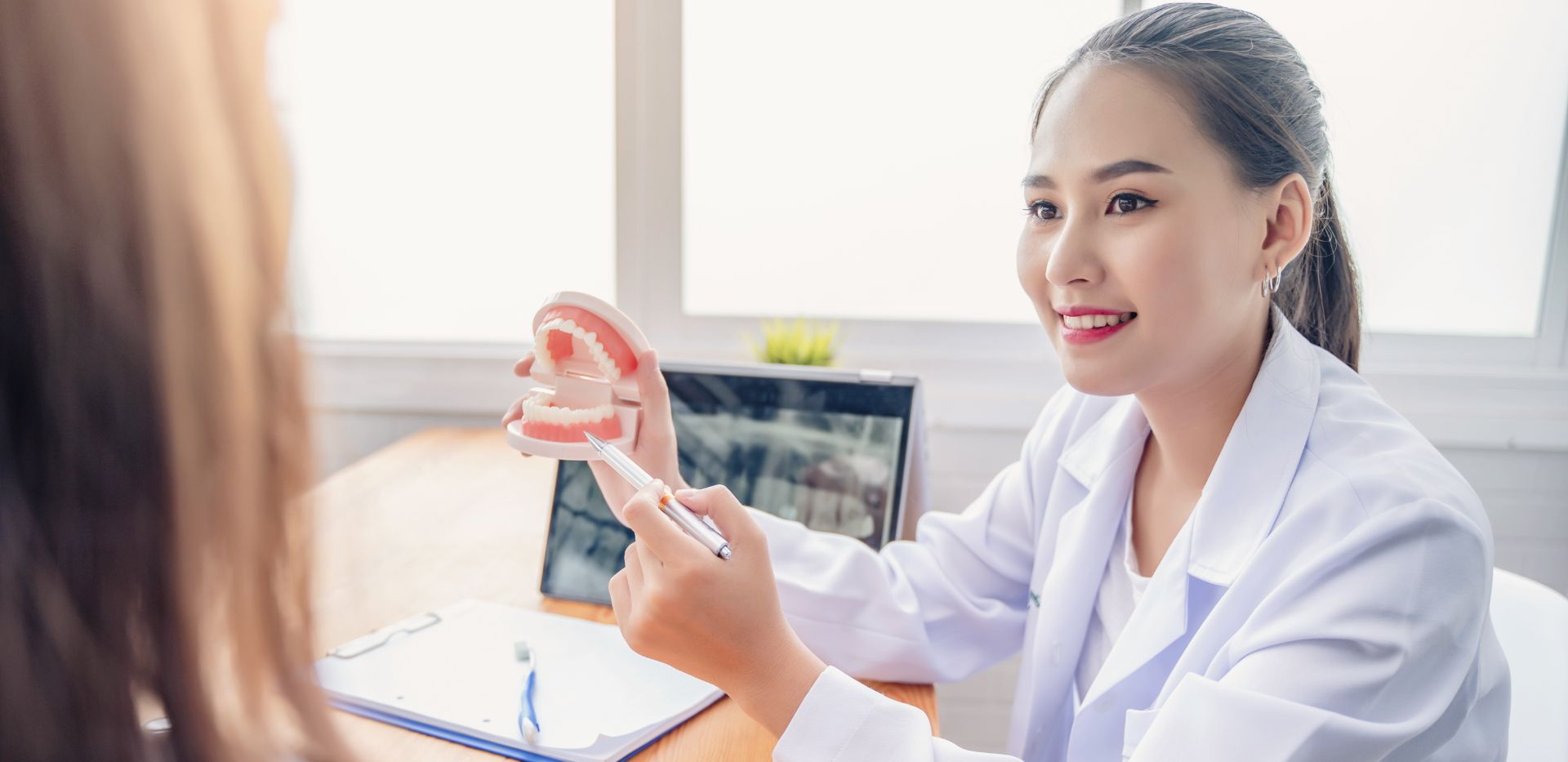 Dentystka pokazuje pacjentce model ludzkiej szczęki
