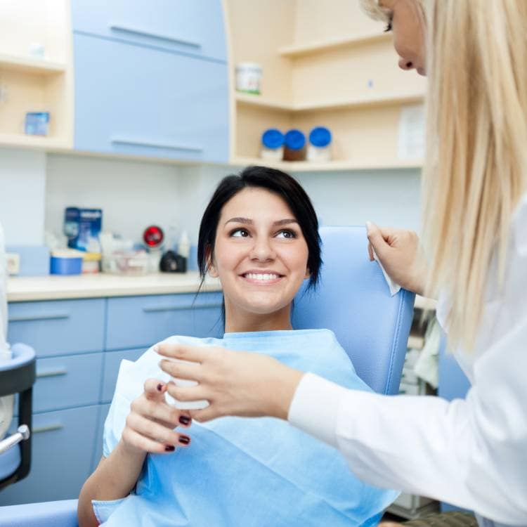 Pacjentka uśmiecha się do dentystki w gabinecie stomatologicznym.