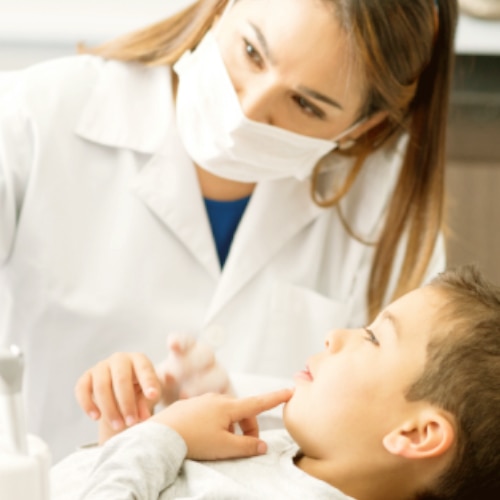 Dentystka przeprowadzająca badanie jamy ustnej młodego pacjenta.