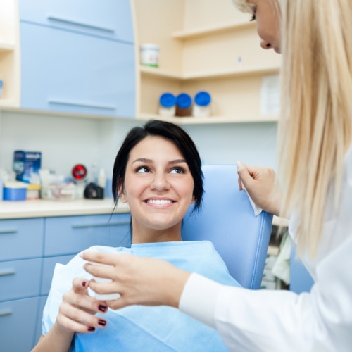 Pacjentka uśmiecha się podczas rozmowy z dentystką w gabinecie stomatologicznym.