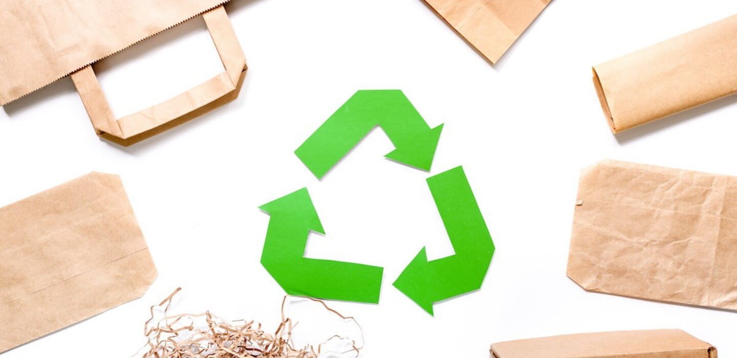 Symbol recyklingu otoczony papierowymi opakowaniami.